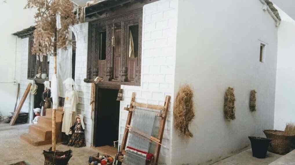 A recreated traditional Rung household display inside the museum, with a loom, woven baskets and mannequins in traditional dress