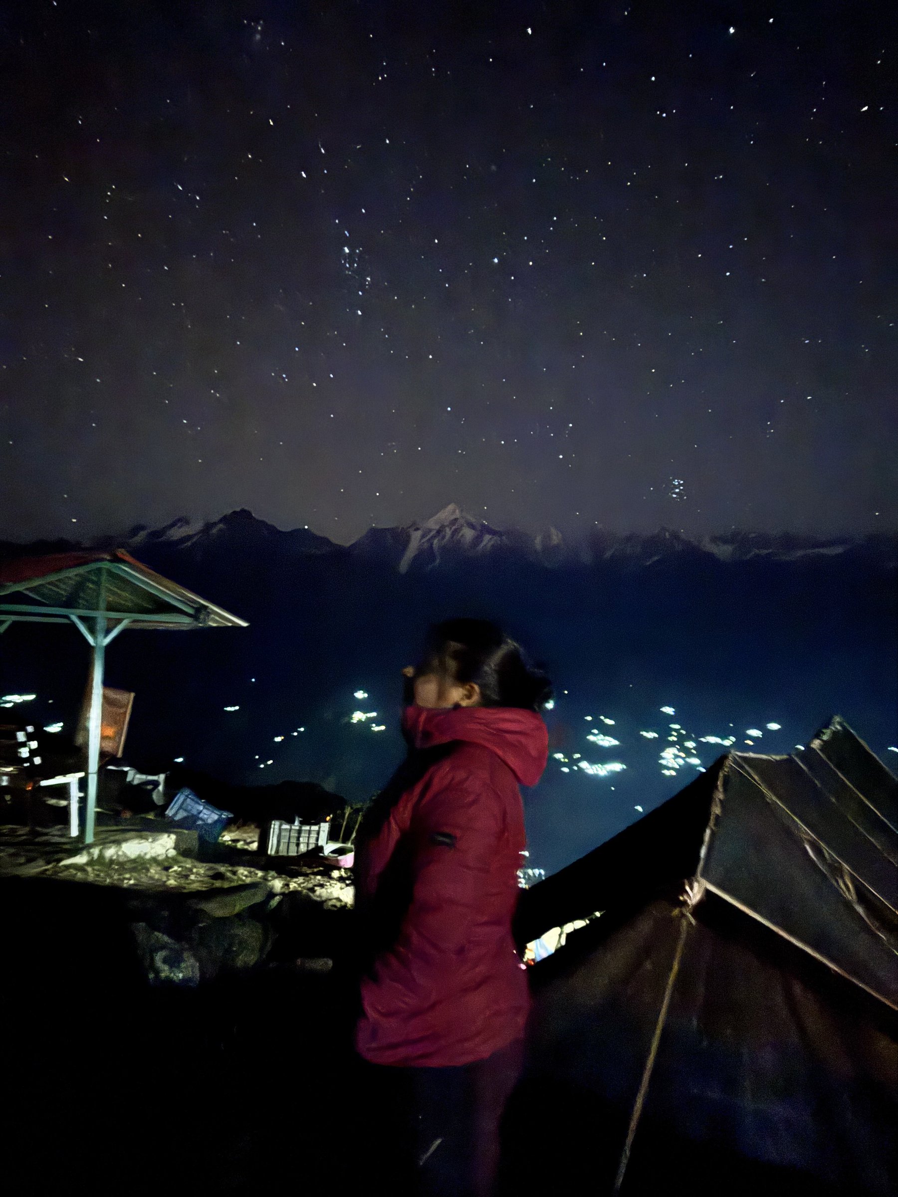 A trekker looking up at the night sky above the Khaliya Top campsite
