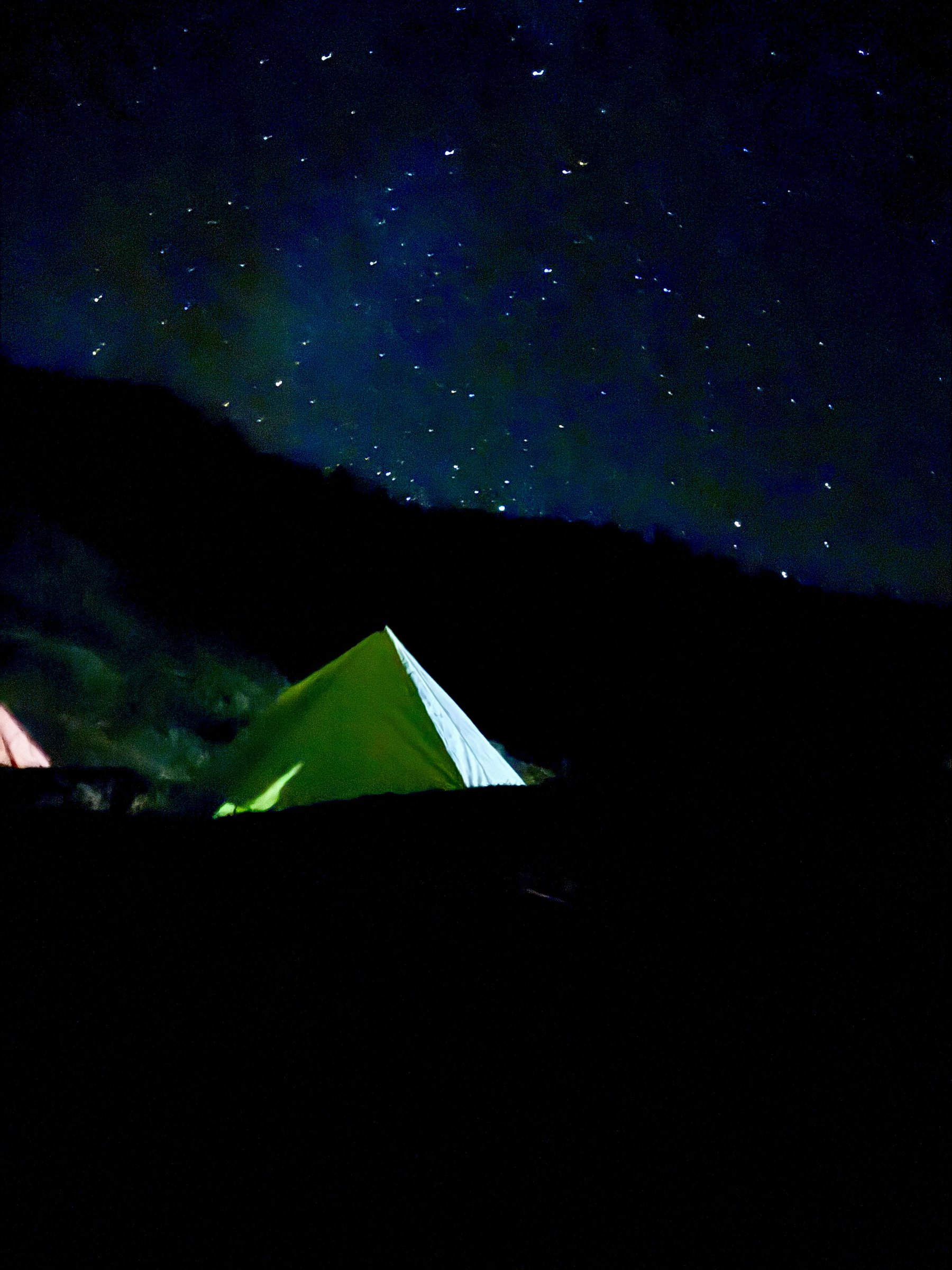 A tent glowing from within under a star-filled sky at Khaliya Top